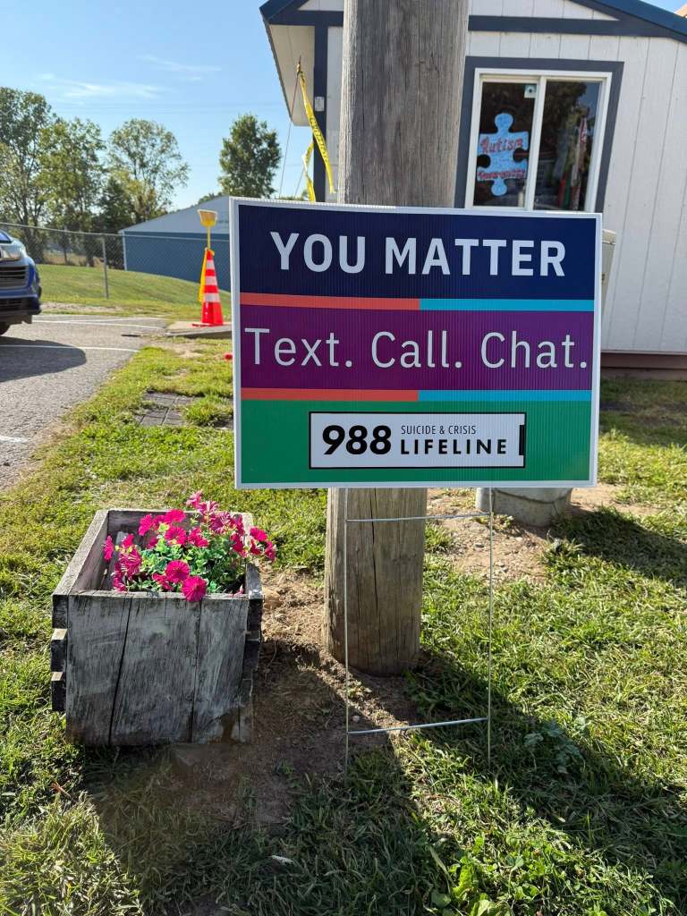 “You Matter” yard sign with the text “Text. Call. Chat. 988 Lifeline” placed in front of a flower planter.